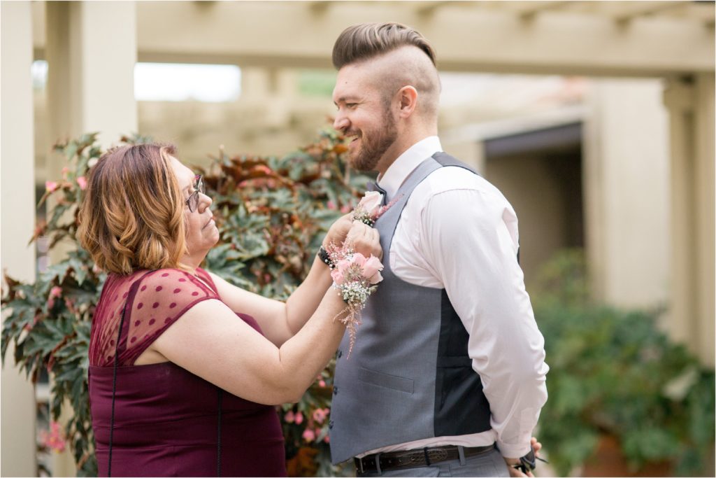 mom pins flower on grooms tux