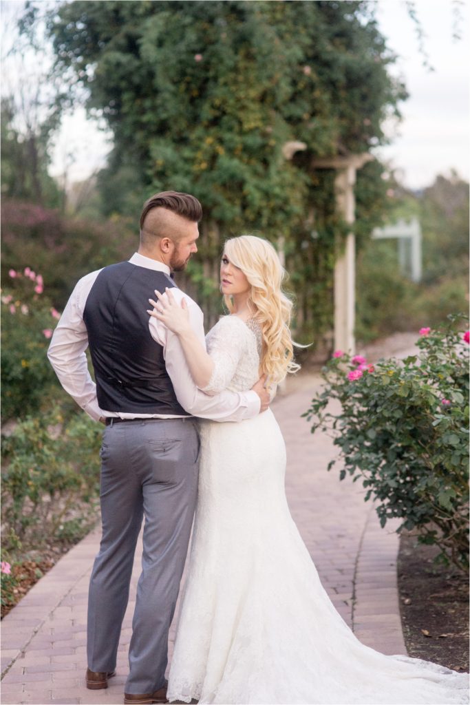 bride and groom pose in rose garden