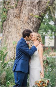 bride and groom kiss in front of tree