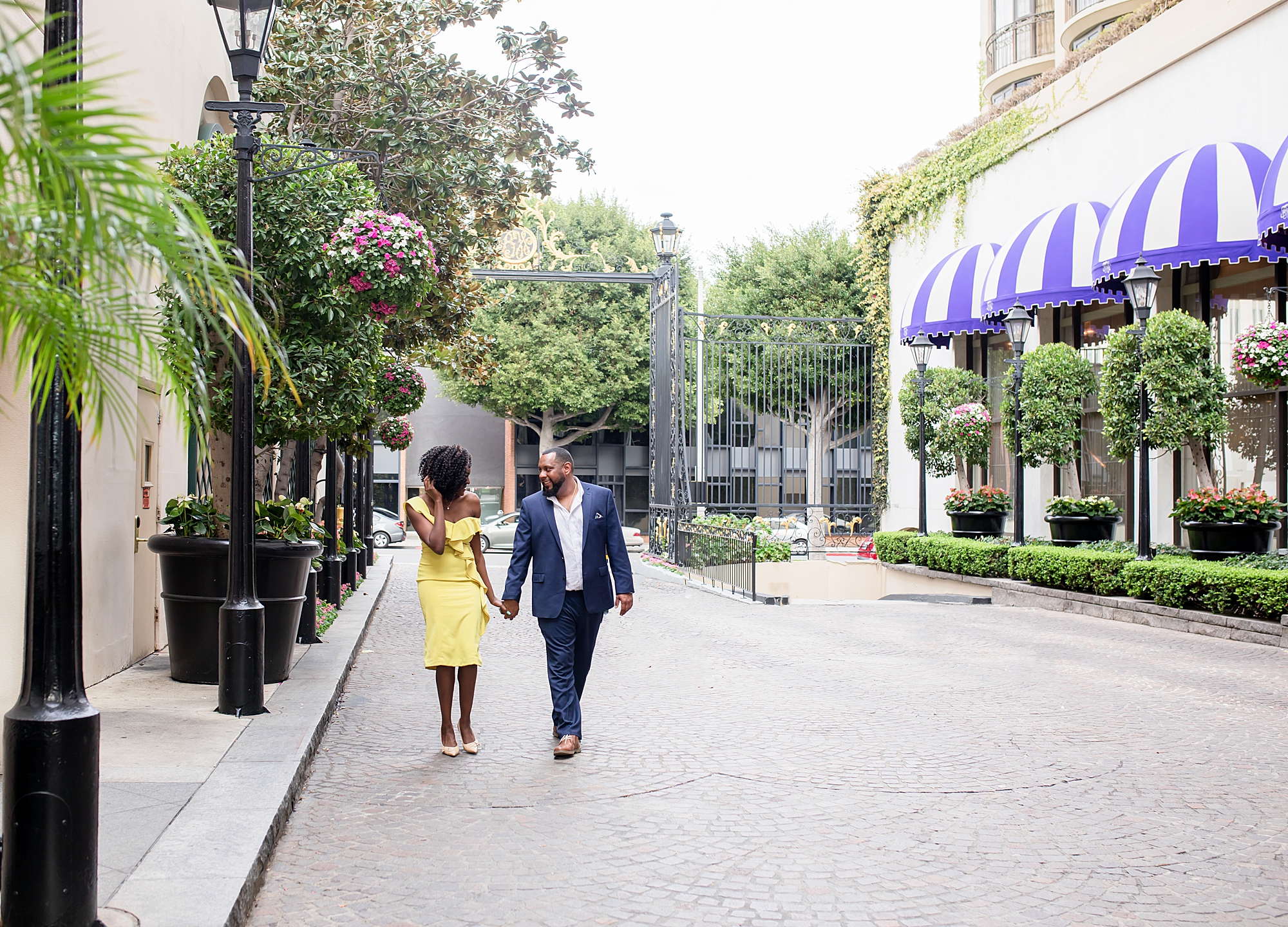 guy in blue suit holding hand with girl in yellow dress for engagement photos in Beverly Hills