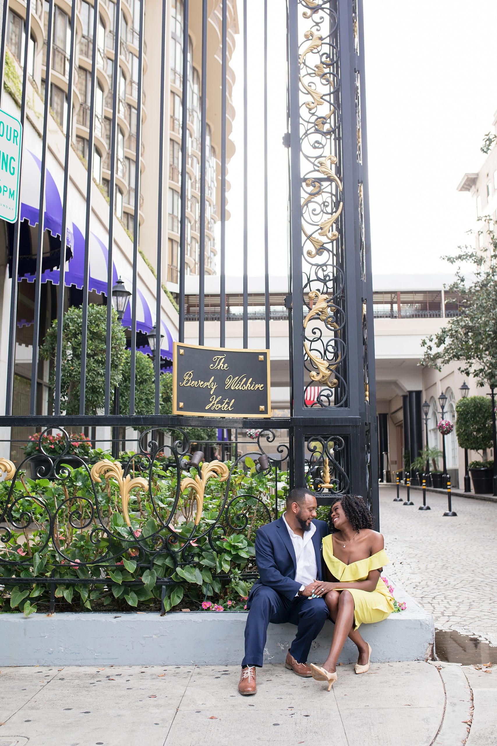 Beverly Hills Wilshire Hotel engagement photography couple sitting by main gate