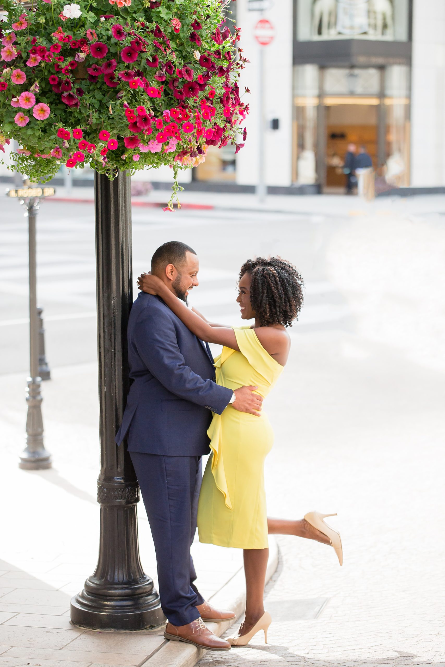 beverly hills engagement couple hugging on the corner of rodeo drive in blue suit and yellow dressphotos by Lisa Marie Photographie,