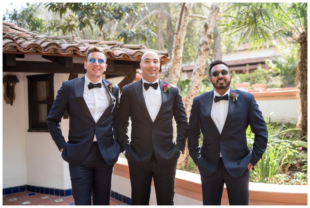 groomsman posing in black suits with bowtie