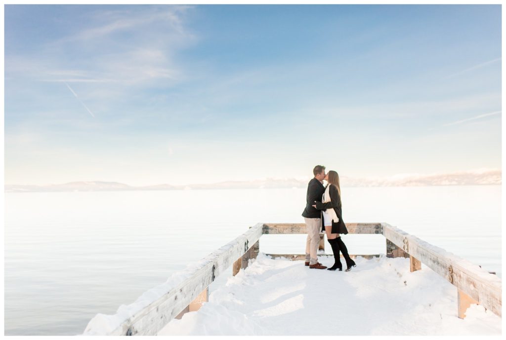 couple kissing on pier by lake