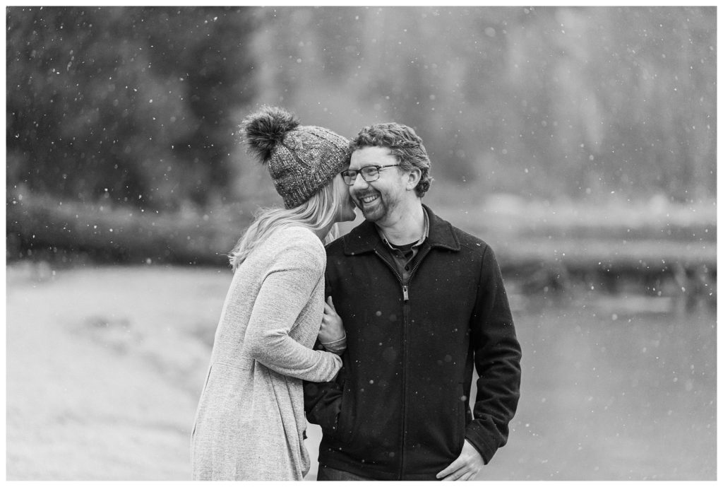 woman whispering in mans ear while it snows