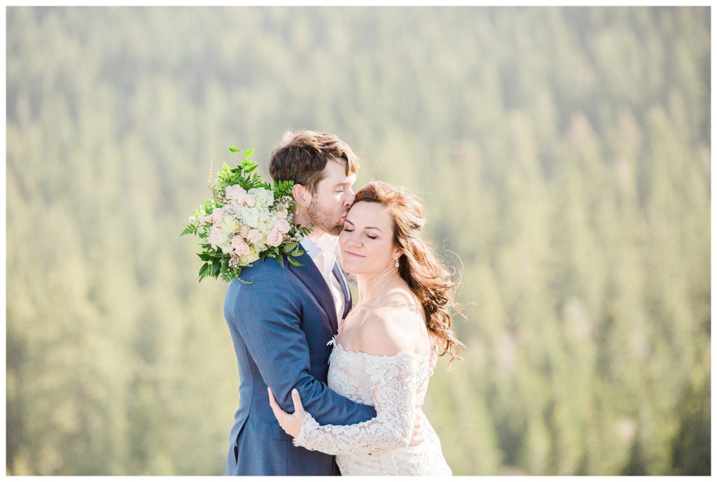 man kissing brides forehead during mountain wedding