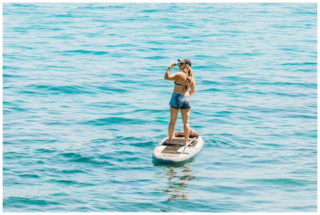 woman sipping beer on paddle board lake tahoe
