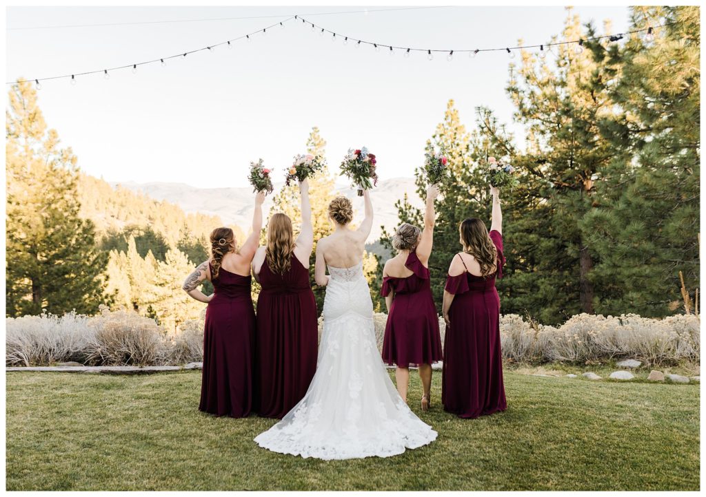 bridemaids facing mountain and holding bouquets in the air