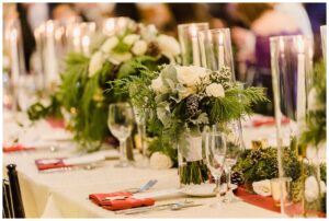 pine greenery decor and red napkins for tables at wedding reception
