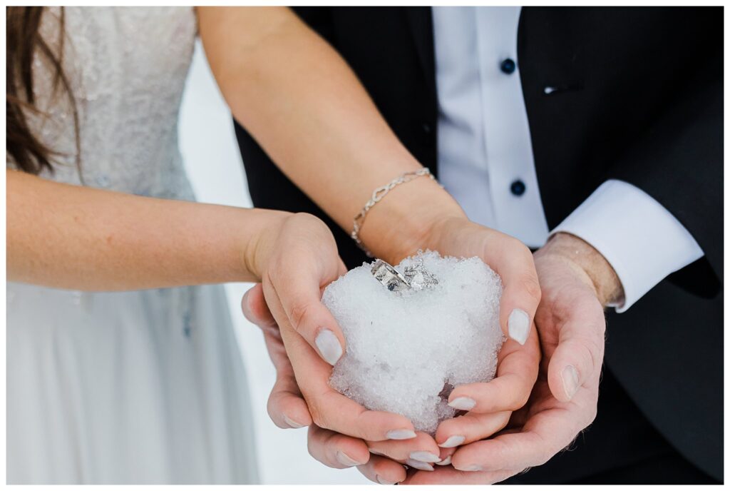couple holding snowball with wedding rings