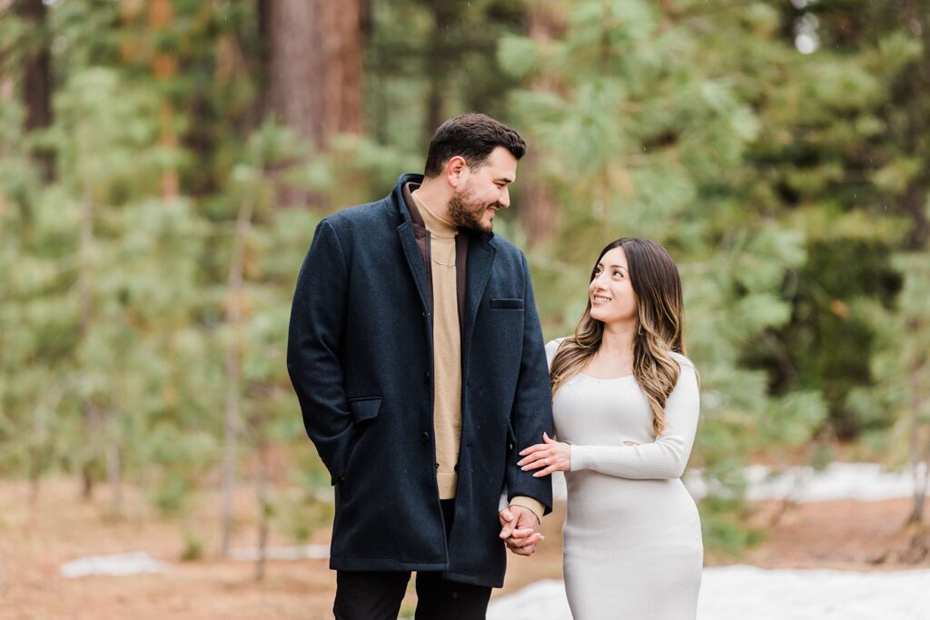 A Lake Tahoe engagement photographer captures a couple holding hands in the snow during their session.