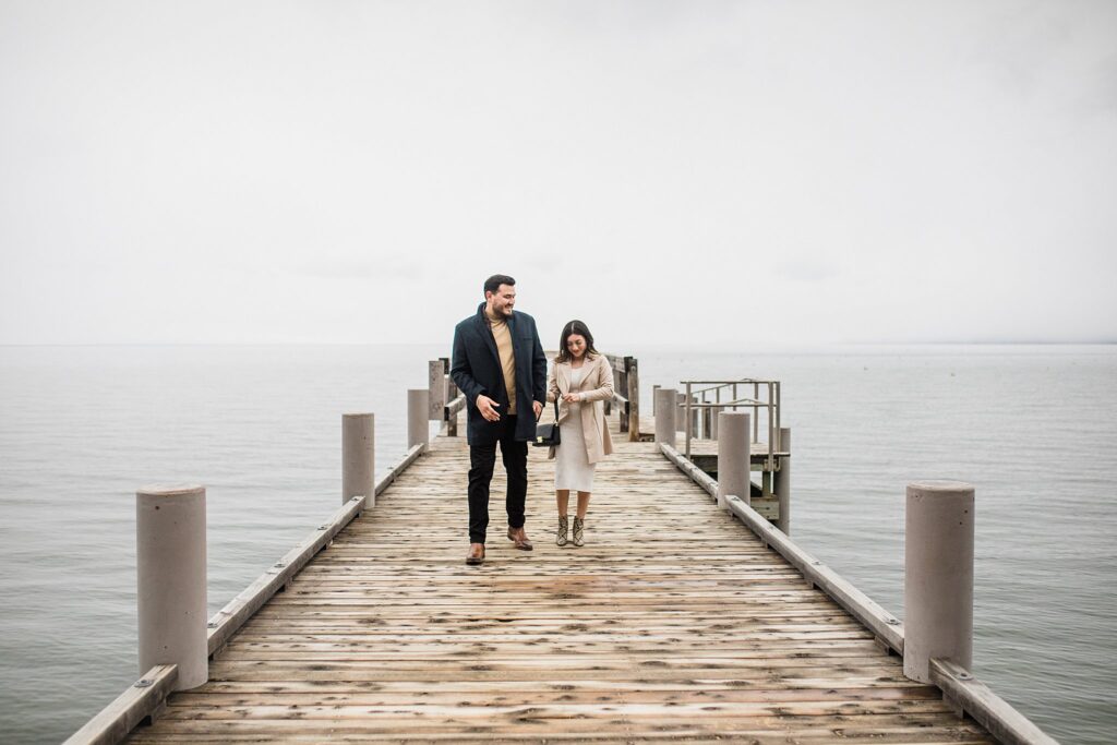 A couple standing on a dock by Lake Tahoe, captured by an engagement photographer on a cloudy day.