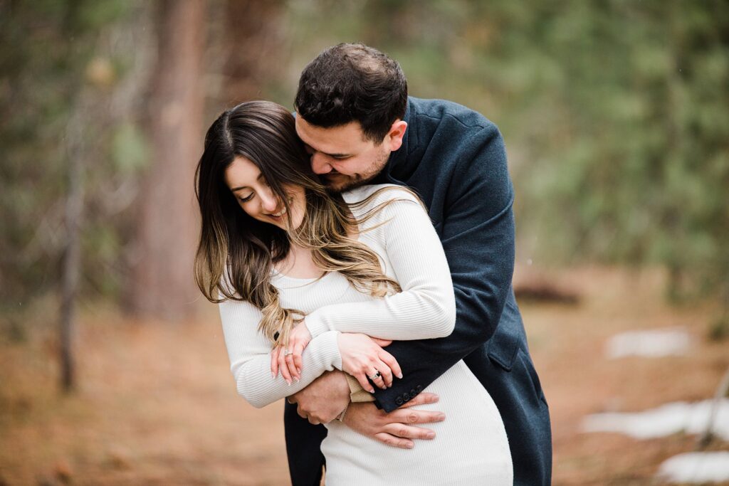 A couple embracing in the woods during their engagement session captured by a Lake Tahoe engagement photographer.