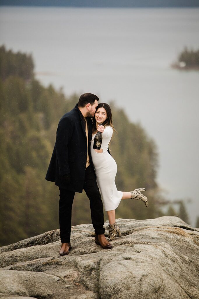 A Lake Tahoe engagement photographer captures the intimate moment of an engaged couple kissing atop a mountain.