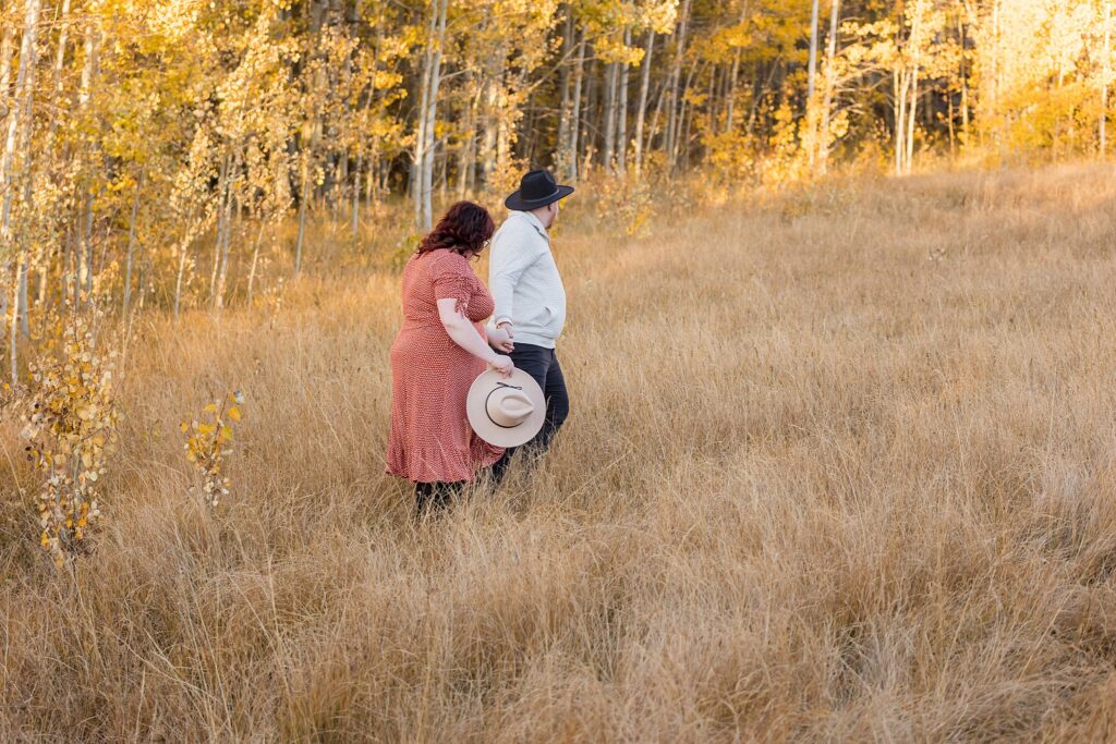 A couple walking in a field of tall grass for Lake Tahoe fall engagement photography.