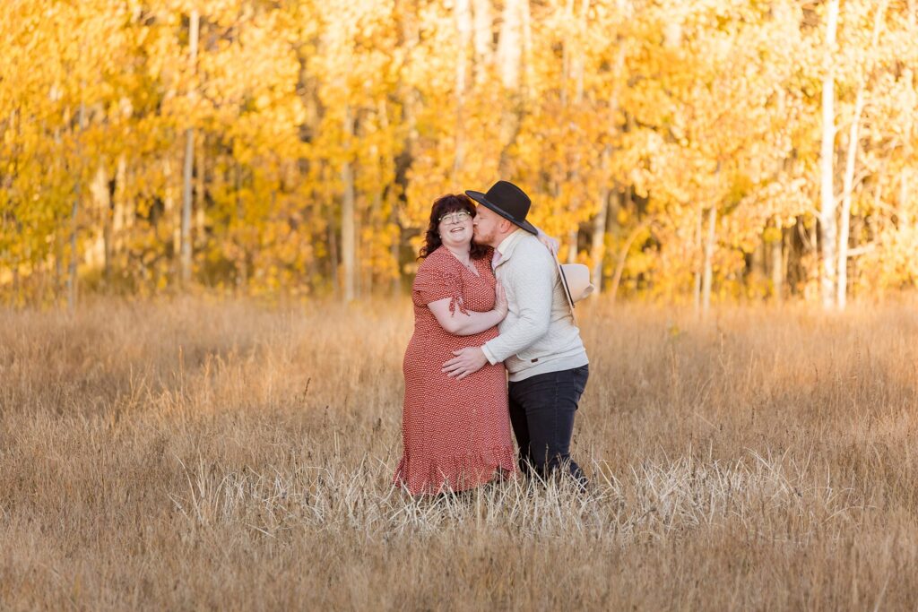 A couple embracing passionately in a picturesque field during their Lake Tahoe fall engagement photography session.