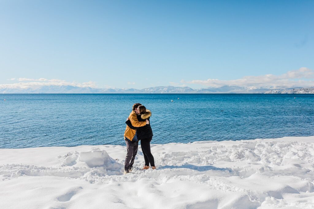 Two people embracing in Lake Tahoe's snowy landscape.