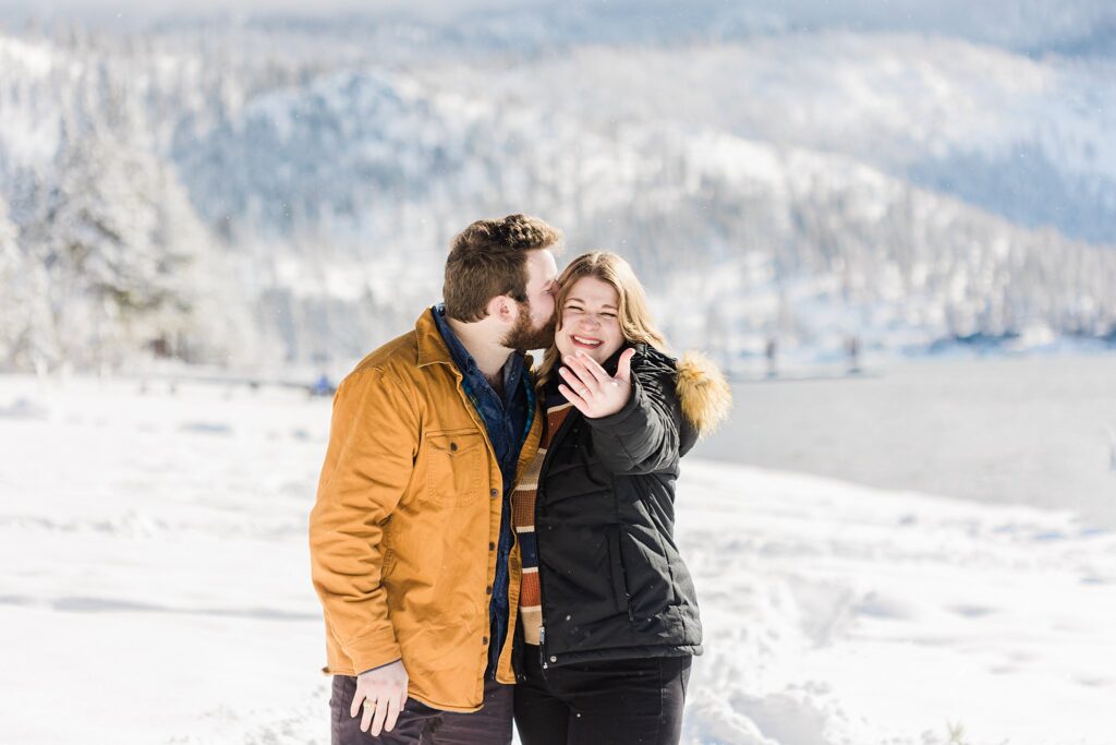 A couple showing the wedding ring amidst the snowy landscape.