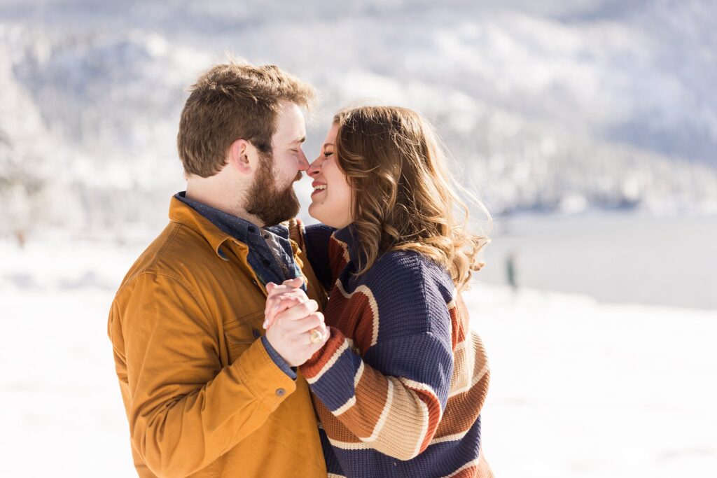 A couple is kissing in the snow during their Lake Tahoe engagement session.