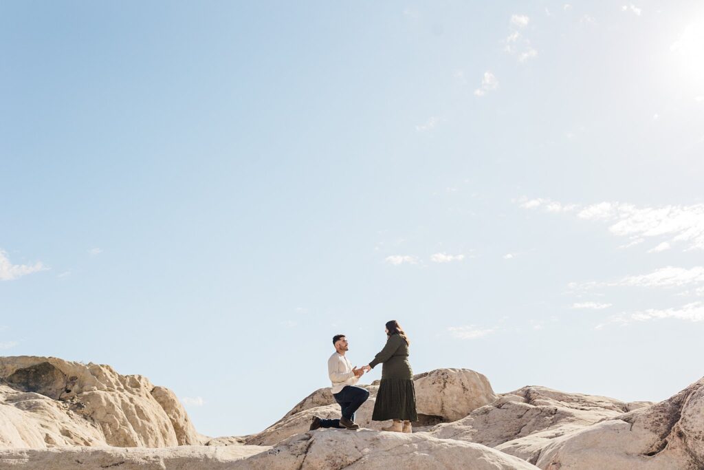 A man and woman are kneeling on a rock in Moon Rocks, Nevada during a proposal photography session.