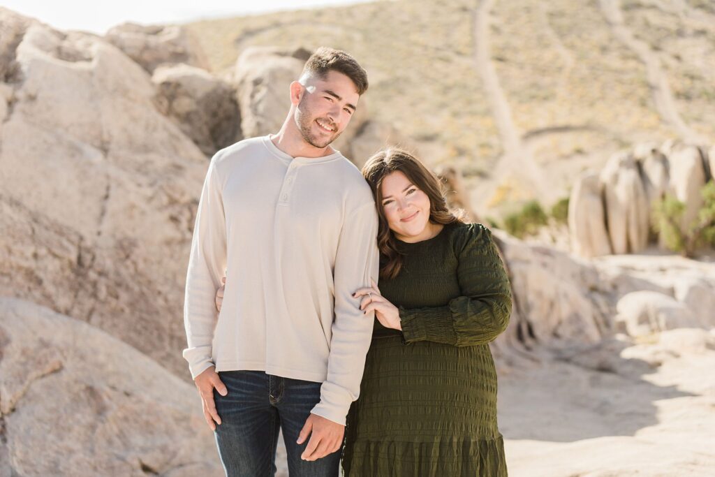A couple standing in front of a rocky area during their engagement session, captured in stunning Nevada proposal photography.