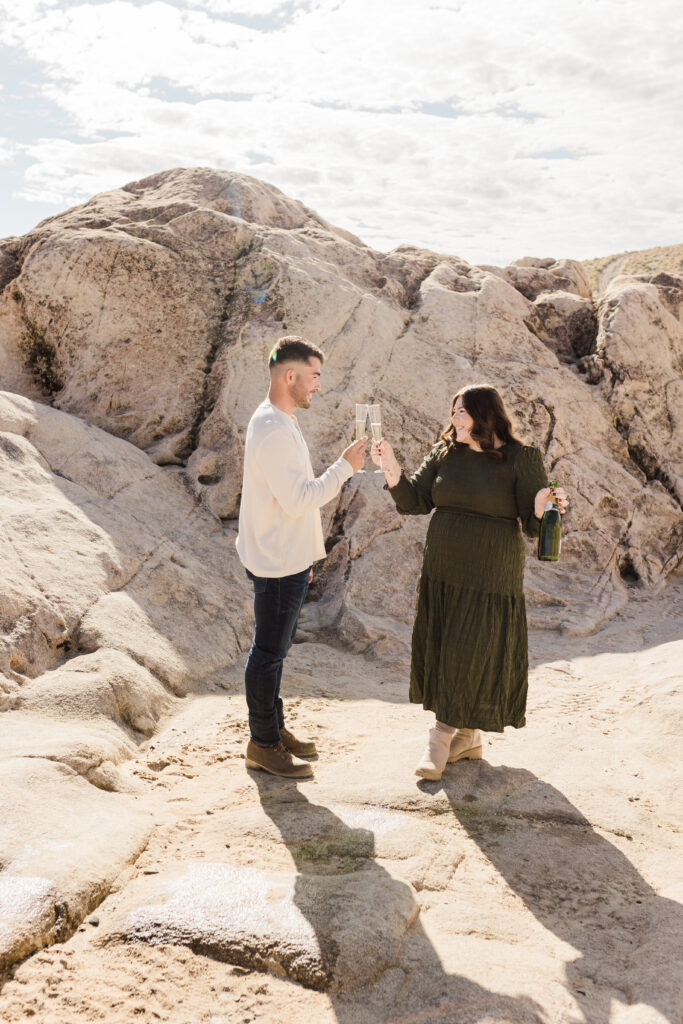 A Lake Tahoe Proposal photographer captures an engaged couple standing on a rock in the desert.