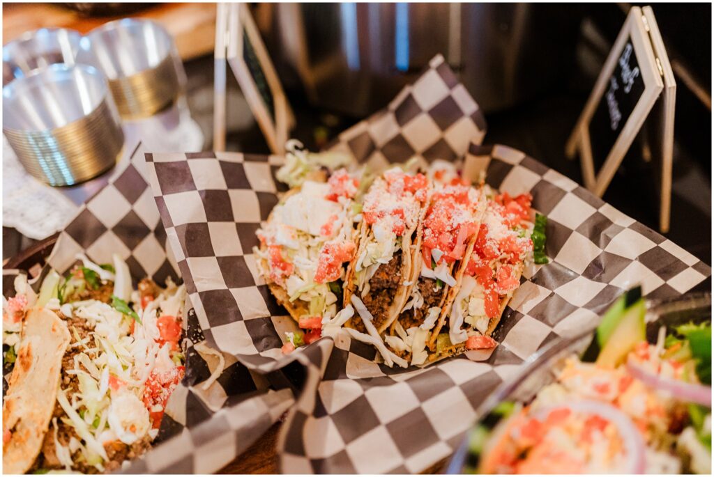 Close-up of a taco on a checkered paper tray, topped with shredded cheese, lettuce, tomatoes, and crumbled topping. This tasty scene is perfect for refueling after exploring the adventurous things to do in Lake Tahoe.